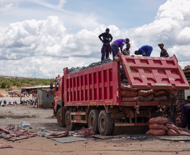 four individuals standing onto of a red truck loading bags